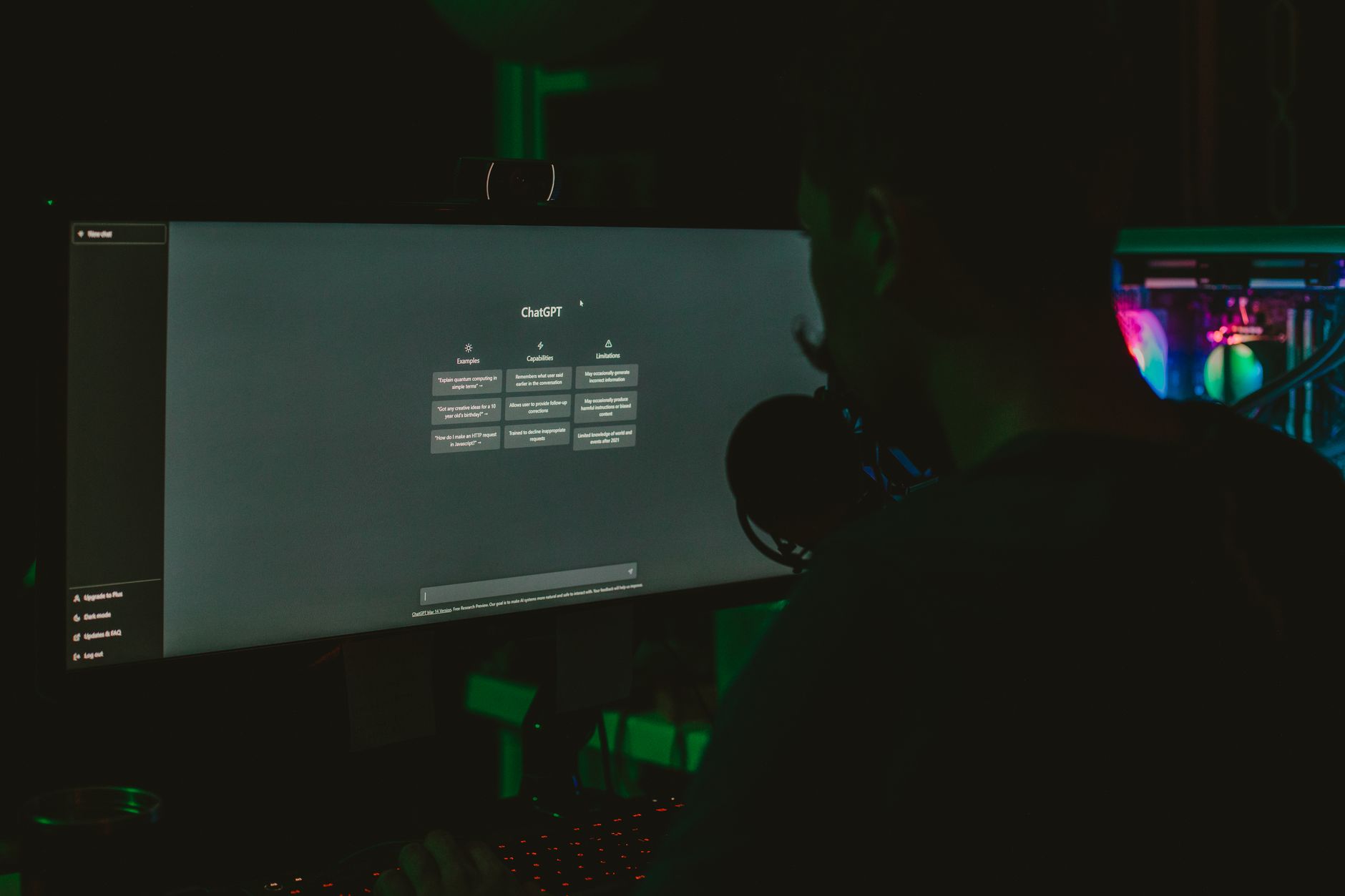 Mężczyzna przy komputerze z dużym monitorem w ciemnym biurze