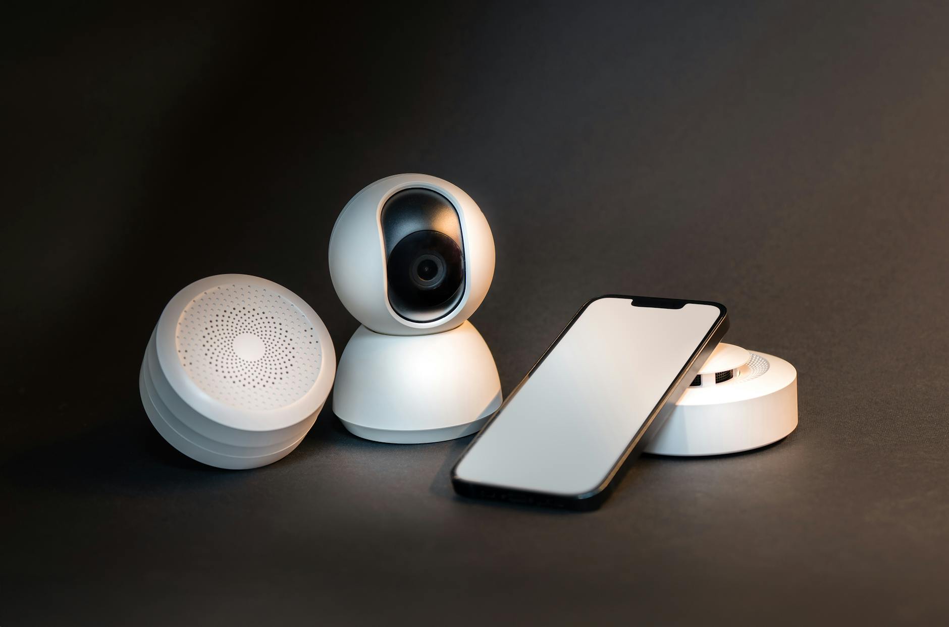 Smartfon obok nowoczesnych urządzeń smart home na szarym tle