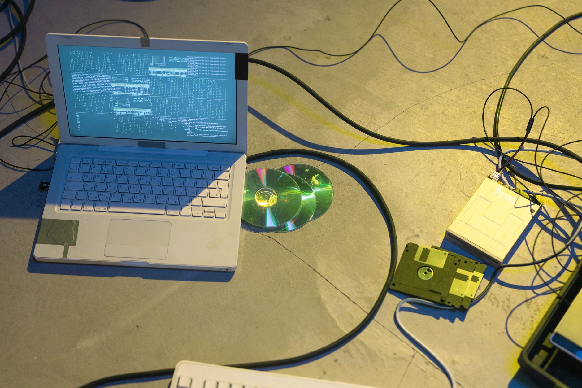 Stare dyskietki i laptop na biurku w plątaninie kabli