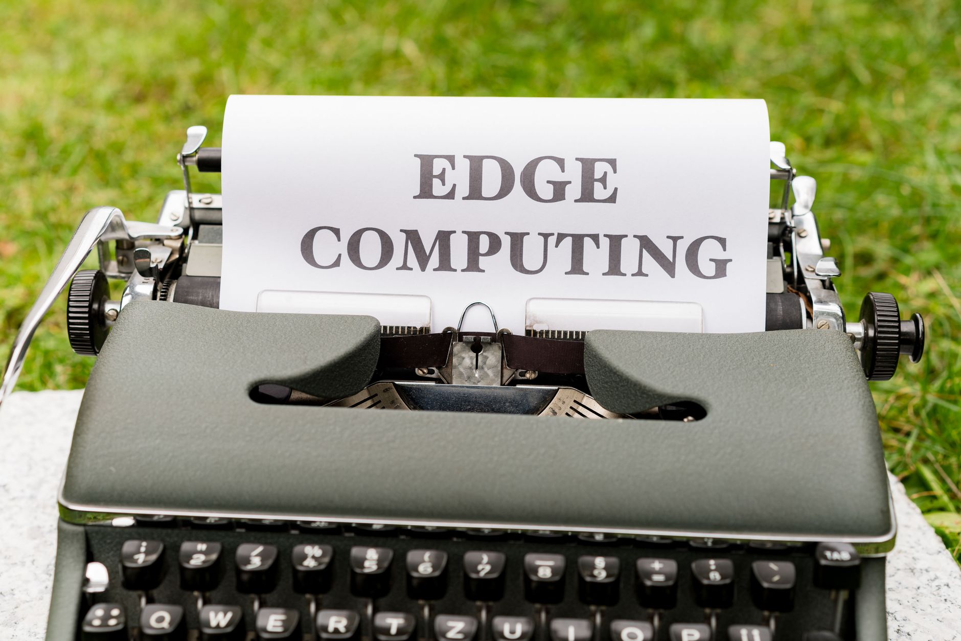 Stara maszyna do pisania na dworze z tekstem EDGE COMPUTING na kartce