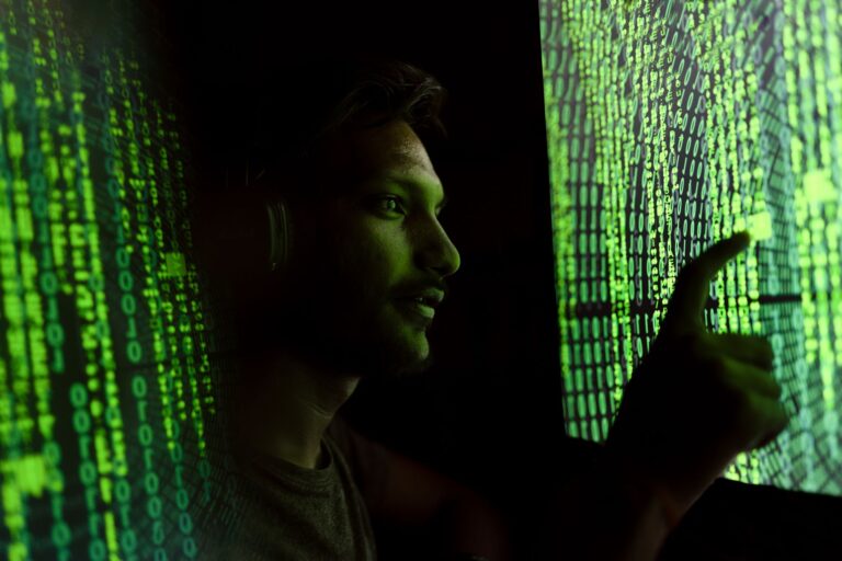 Osoba pracująca z kodem cyfrowym na ekranie, symbol cyberbezpieczeństwa