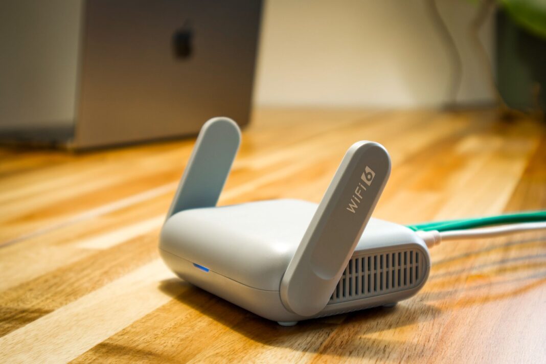 Router Wi‑Fi 6 z antenami i przewodem na drewnianym biurku